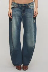 Jeans de tiro bajo confeccionados en denim 100% algodón, con diseño de pierna curva y sutiles desgastes en tono azul vintage.