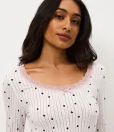 Blusa de pijama de manga larga con escote redondo adornado con encaje y un pequeño lazo central. Presenta un estampado de corazones pequeños sobre un fondo de rayas verticales finas.