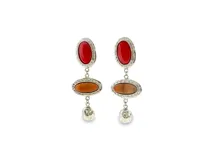 Pendientes colgantes de metal plateado con incrustaciones de resina en tonos rojo intenso y marrón rojizo. Tienen un diseño con borde texturizado y un pequeño colgante de metal martillado en la parte inferior.