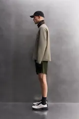 Bermuda de hombre color verde militar, de corte regular fit, confeccionada en tejido técnico compacto con elasticidad. Presenta cintura ajustable con cinturón a contraste, bolsillos frontales y un bolsillo plastrón con cierre de cremallera oculta en una de las perneras.