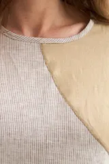 Blusa de silueta amplia y relajada, confeccionada en lino con cuello redondo, mangas cortas y recorte diagonal en el frente.