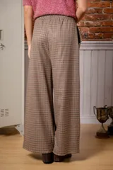 Pantalón de corte ancho y tiro alto, con estampado de cuadros pequeños en tonos marrones y negros. Cuenta con cintura elástica y cordón ajustable.