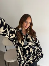 Buzo de peluche con estampado animal print de leopardo, cuello alto con cierre frontal parcial y tirador metálico decorativo.