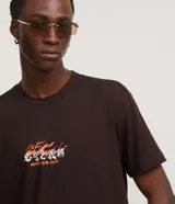 Remera marrón de algodón con cuello redondo y mangas cortas. Estampa en la espalda con diseño de máscara japonesa, serpiente, espadas y flores. Estampa frontal con la frase "Honor and Duty".