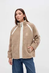 Campera de sherpa color marrón con diseño capitoneado, cierre frontal completo y detalles en color blanco. Presenta cuello alto, bolsillos laterales y puños elásticos.