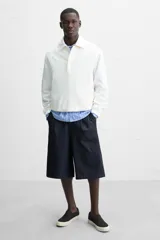 Zapatilla slip-on negra de tejido de algodón con elásticos laterales y suela color crema.