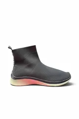 Bota corta de punto tipo zapatilla, color gris, con diseño slip-on estilo media caña y suela con detalle degradado en tonos rosados y blancos.