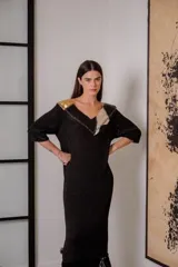 Vestido corto negro de tejido de punto con cuello en V, mangas 3/4, flecos en el ruedo y apliques de cuero en escote y hombros.