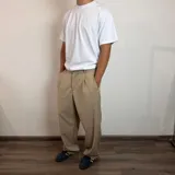 Pantalón sastrero color beige, de corte baggy, con pliegues en la cintura y bolsillos laterales.
