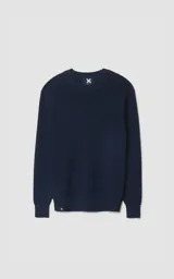 Sweater de tejido de punto en color azul marino, con cuello redondo y diseño clásico de manga larga. Presenta un pequeño detalle de etiqueta con logo en el ruedo.