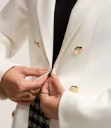 Blazer blanco de punto roma con cuello solapa, corte sastrero alargado, bolsillos y cierre con corchete.