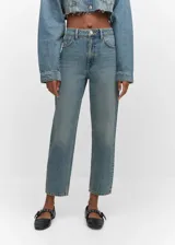 Jeans de tiro alto con corte mom-fit, confeccionados en tejido de algodón estilo tejano. Presentan diseño de cinco bolsillos, trabillas para cinturón y cierre frontal con cremallera y botón.