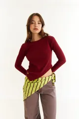 Top de manga larga color blanco, confeccionado en tejido de punto acanalado con diseño irregular y aberturas para los pulgares en los puños.