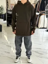 Canguro oversize chocolate con capucha, confeccionado con un diseño urbano que incluye un gran estampado gráfico en la espalda con líneas onduladas y texto.