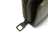 Billetera XL de textura granulada en color verde militar, con cierre perimetral y solapa frontal con broche decorado con una flor metálica.