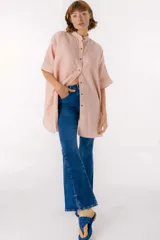 Camisa de lino a rayas rosadas y blancas, con cuello mao, manga corta con puño, botones de metal a la vista y ruedo camisero con tajos laterales.