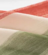 Pareo rectangular de chiffon con estampado botánico de hojas de buriti en tonos verdes, rojos y beige. Presenta un diseño ligero y versátil con detalle de borlas en los extremos.