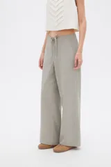 Pantalón de algodón color gris, de tiro medio y corte holgado tipo baggy, con bolsillos laterales y cordón ajustable en la cintura.