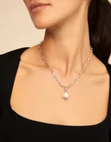Dije colgante dorado con una perla blanca.
