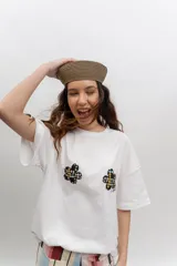Remera de algodón blanca, de corte oversize, con mangas cortas y dos aplicaciones de flores bordadas en el frente.