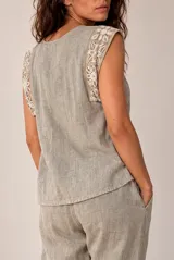 Blusa de lino color beige sin mangas, con cuello redondo y detalles de crochet en los hombros.