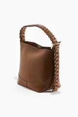 Cartera tipo hobo de diseño estructurado en color marrón, con costuras visibles en contraste y correa de hombro trenzada en tonos marrón y negro con hebilla metálica lateral.