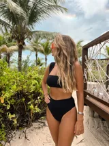 Conjunto de bikini negro de hilo, con corpiño bandeau y bombacha vedetina de tiro alto.