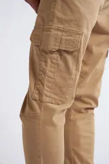 Pantalón cargo de corte slim, color beige, con cierre y botón frontal, bolsillos laterales tipo cargo y terminación recta sin puños.