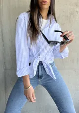 Camisa de manga larga con rayas verticales celestes y blancas, de corte recto y largo con aberturas laterales.