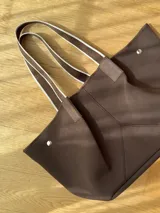 Bolso tipo tote de neopreno en color verde oliva, con correas de hombro en color rojo y detalles en blanco. Cuenta con broches imantados laterales para ajustar su forma y un bolsillo interno de red.