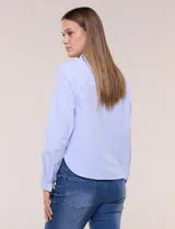 Camisa de algodón celeste con patrón de milrayas finas y aplicaciones florales en relieve deshilachado en el frente. Cuenta con cuello camisero tradicional, cierre frontal con botones, mangas largas con puños abotonados y corte semi holgado.