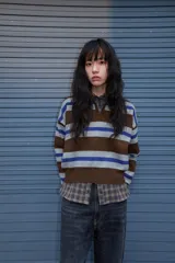 Jersey de punto con diseño a rayas horizontales en tonos marrón, gris y azul. Presenta cuello tipo polo con abertura frontal, manga larga y puños acanalados.