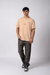 Remera de algodón con efecto lavado gastado, cuello redondo y mangas cortas. Presenta estampados minimalistas en el frente con el logo de la marca y la frase 'Local Based, Global Attitude'.