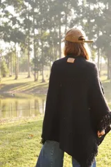 Poncho tejido en lana merino color crudo, con cuello alto y etiqueta de cuero con logo en la espalda.