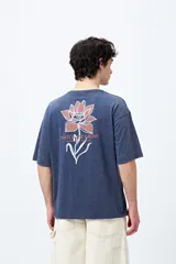 Remera negra de corte holgado con mangas cortas amplias y cuello redondo. Estampado pequeño de flor en el pecho y estampado grande en la espalda con diseño floral y texto.