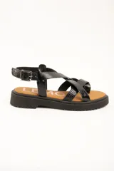 Sandalias negras de cuero con tiras entrelazadas en el empeine, suela flatform dentada y tira ajustable con hebilla en el talón.