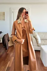 Trench largo de cuero ovino color camel, con cuello camisero en contraste color crema y mangas con puños vueltos en tono chocolate. Diseño abierto con bolsillos laterales amplios.