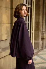 Campera de corte holgado y diseño minimalista en color marrón, con cuello alto, cierre frontal oculto y mangas largas con puños ajustados.