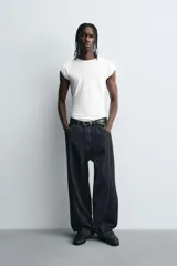 Jeans de denim oscuro, corte ancho (baggy fit) y tiro medio, con costura central girada en el frente de ambas piernas. Presenta pespuntes en color caramelo.