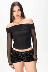 Top negro de manga larga confeccionado en tela semitransparente, con diseño off-shoulder y escote bote drapeado.