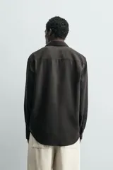 Camisa de corte relajado confeccionada en tejido fluido de lyocell. Presenta cuello solapa, manga larga con puños abotonados y cierre frontal con botones.