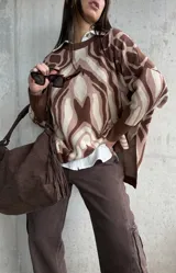 Sweater de tejido de punto con diseño estampado abstracto en tonos marrones y beige, de corte oversize, cuello redondo y mangas largas con puños acanalados.