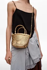 Bolso mini trenzado color dorado, con doble asa corta de mano y correa larga para el hombro. Incluye parche con logo grabado en el frente.