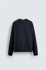 Camiseta de manga larga con cuello redondo, confeccionada en algodón compacto y pesado, con diseño de corte relajado y costuras decorativas en el cuello.