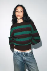Jersey de punto con diseño de rayas horizontales en tonos marrón, verde y fucsia. Presenta cuello redondo, manga larga y terminaciones en rib.