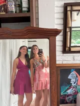 Vestido corto negro con estampado de plumas doradas, escote en V, breteles finos cruzados en la espalda, cut-outs laterales y volado en el ruedo.