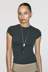 Camiseta de corte entallado confeccionada en mezcla de algodón, con cuello redondo y mangas cortas. Presenta un diseño básico de bajo recto en color gris oscuro.