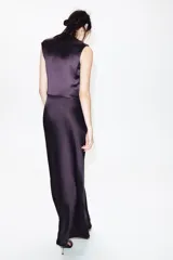 Vestido largo color morado de tejido satinado, sin mangas, con cuello fluido y detalle de drapeado en el lateral.