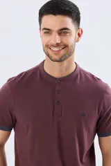Remera estilo polo con cuello mao y manga corta, de color bordó con detalles en azul en los bordes de las mangas y cuello. Cuenta con cierre frontal parcial de tres botones y pequeño logo bordado en el pecho.