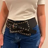 Cinto faja ancho de cuero genuino color marrón, con diseño de estilo ecuestre y detalles de tachas metálicas a lo largo de toda la pieza. Cuenta con cierre mediante hebilla metálica ajustable.